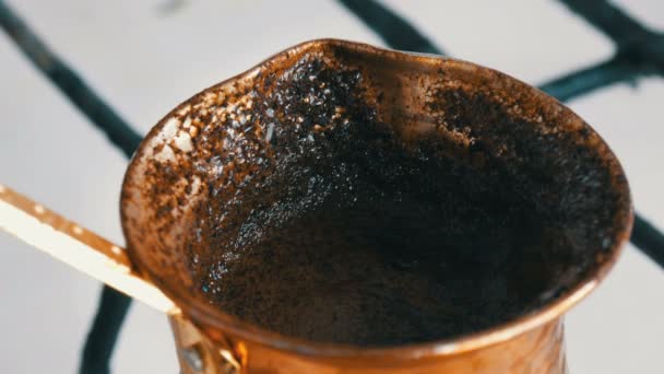 Weggekookt weggelopen gemalen zwarte koffie in een koper Turk op witte gaskachel — Stockvideo