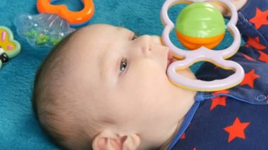 Bebek çıngırakları ile çevrili mavi bir yatak örtüsü üzerinde yatan iki aylık güzel komik küçük yenidoğan bebek Portresi