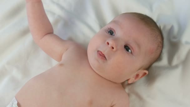 Retrato de hermoso bebé recién nacido divertido de dos meses acostado en la cama blanca — Vídeo de stock