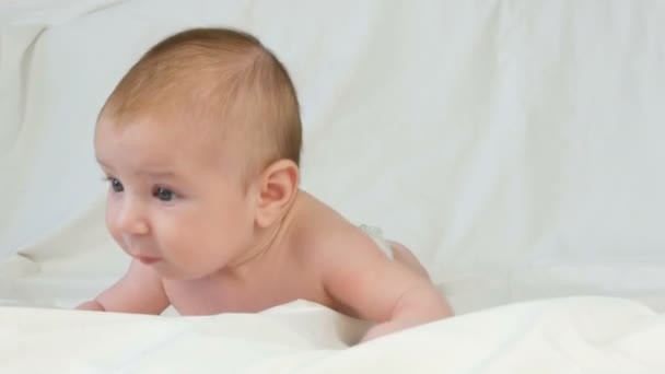 Portret van mooie grappige kleine pasgeboren baby van twee maanden liggend op wit bed — Stockvideo