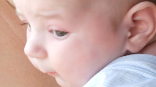 2ヶ月の新生児は、母親の腕の周りを見回す上に横たわっている — ストック動画