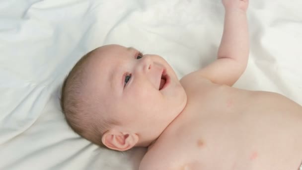 Portret van mooie grappige kleine pasgeboren baby van twee maanden liggend op wit bed — Stockvideo