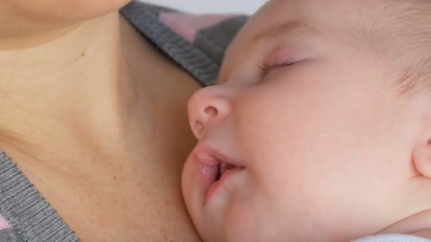Молодая красивая мама с длинными темными волосами держит новорожденного младенца двух месяцев на белом фоне в студии — стоковое видео