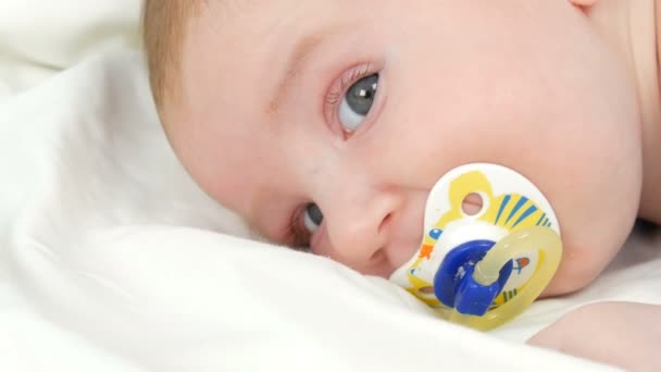 Mother gently touches and cradles her newborn baby in arms while sitting on her bed. The childs face close up view — Stock Video