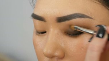 Profesyonel makyaj sanatçısı özel fırça ile Koreli kız Asyalı kadın göz makyajı yapar