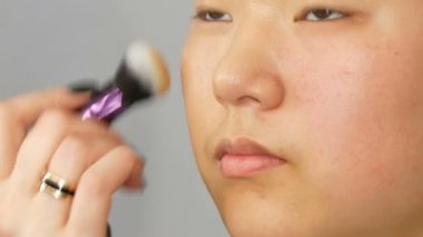 Profesyonel makyaj sanatçısı özel fırça ile Asya Koreli modeller yüz vakıf kapatıcı veya vurgulayıcı uygular