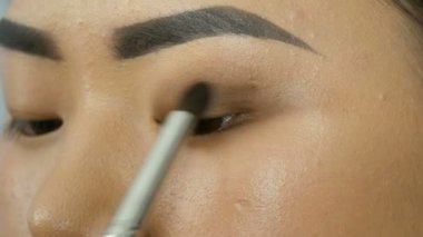 Profesyonel makyaj sanatçısı özel fırça ile Koreli kız Asyalı kadın göz makyajı yapar