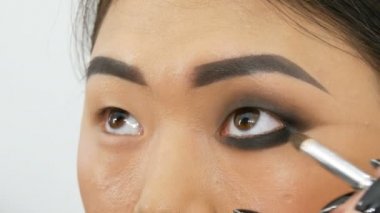 Profesyonel makyaj sanatçısı özel fırça ile Koreli kız Asyalı kadın göz makyajı yapar