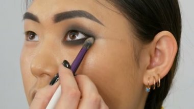 Profesyonel makyaj sanatçısı özel fırça ile Koreli kız Asyalı kadın göz makyajı yapar