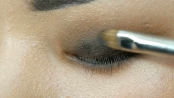 Профессиональный визажист делает макияж глаз корейской девушки азиатки со специальной кистью — стоковое видео