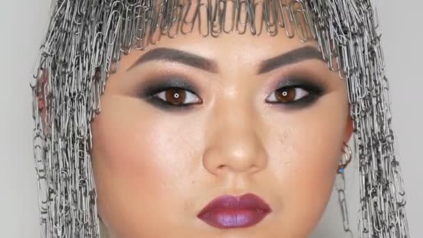 Belle fille asiatique coréenne dans une perruque de papeterie avec des yeux fumés de maquillage de soirée lumineux posant en studio sur un fond blanc, haute couture — Video