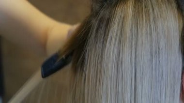Bir güzellik salonunda özel ütü ile sarı uzun saç düzleştirme
