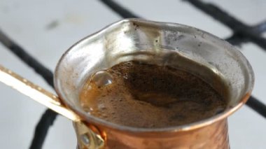 Bakır bir Türk'te çekilmiş siyah kahve demlenir ve gaz sobasında kaynatılır. Barista evde sıcak lezzetli içecek hazırlarken yakın