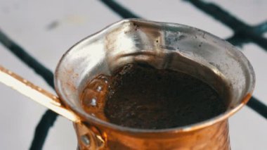 Bakır bir Türk'te çekilmiş siyah kahve demlenir ve gaz sobasında kaynatılır. Barista evde sıcak lezzetli içecek hazırlarken yakın