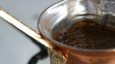 Bakır bir Türk'te çekilmiş siyah kahve demlenir ve gaz sobasında kaynatılır. Barista evde sıcak lezzetli içecek hazırlarken yakın