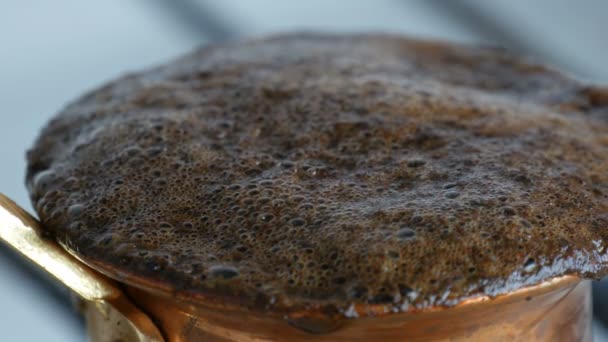 Abgekochter, gemahlener schwarzer Kaffee in einem Kupfertürken auf weißem Gasherd Nahaufnahme — Stockvideo