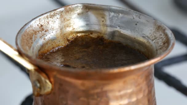 Il caffè nero macinato in un turco di rame è preparato e bolle su una stufa a gas. Barista preparare bevanda calda gustosa a casa da vicino — Video Stock