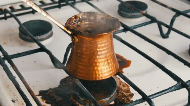 Abgekochter, gemahlener schwarzer Kaffee in einem Kupfertürken auf weißem Gasherd — Stockvideo