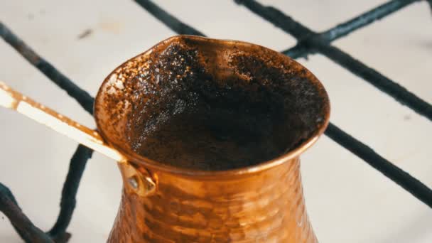 Café noir emballé bouilli dans une turque de cuivre sur une cuisinière à gaz blanche — Video