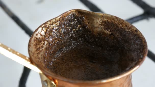 Вареный сбежавший молотый черный кофе в медном тюрке на белой газовой плите — стоковое видео