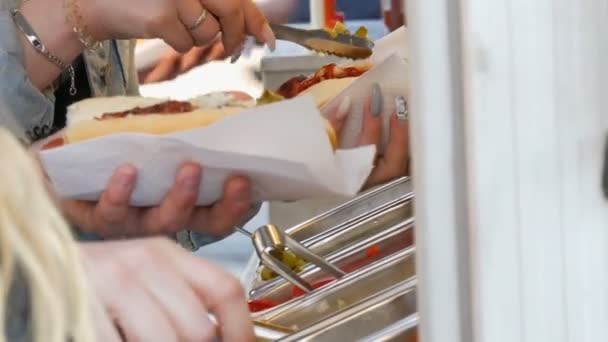 Dívky v rukou si na Hot Dogu vydělají různá ochutka ve speciálním stánku pouličních jídel, rychlé občerstvení na ulici Amsterdam. — Stock video