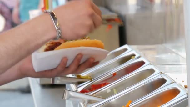 As mãos de homem põem vários seasonings em um cachorro-quente no quiosque especial da comida de rua, comida rápida na rua de Amsterdã . — Vídeo de Stock