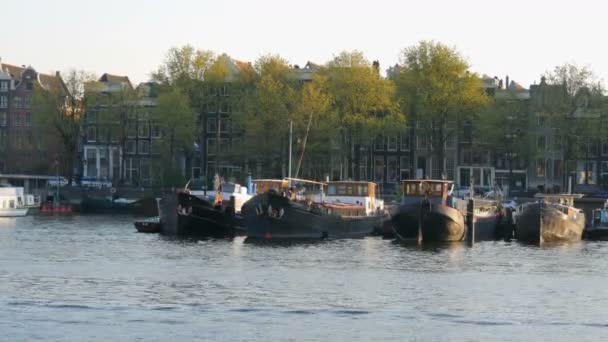 Amsterdamse grachten, waarop afgemeerd boten. Authentieke Nederlandse huizen en straten van de hoofdstad van Nederland — Stockvideo