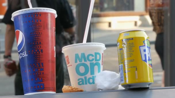 Ámsterdam, Países Bajos - 21 de abril de 2019: Un cubo de basura con gafas Pepsi, Fanta y McDonalds de pie. Consumismo, mala alimentación, comida rápida, bebida dulce — Vídeos de Stock