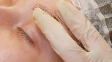 Uzman kozmetik uzmanı renk kaşlarına pigment uyguluyor. Mikro patenli kaş şekli düzeltmesi. Dövme, kalıcı makyaj, yakın çekim pudrası.