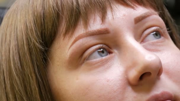 Una mujer joven en una sala de cometología con una pulverización de polvo microestocástico acaba de hacer corrección de cejas. Maquillaje permanente. Tatuaje Nuevas tecnologías en cosmetología — Vídeo de stock