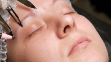 Güzellik uzmanlarının elleri, hastaların yüzlerindeki yeni kaş şekillerinin işaretlerini özel aletler, bir kalem ve pusula yardımıyla yapıyor. Pudra püskürtme, mikro patinaj, dövme, kalıcı makyaj.