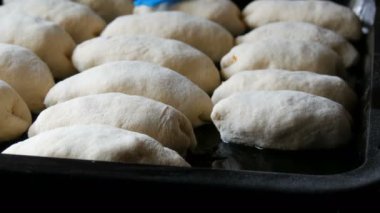 Kadın el fırıncısı, ev yapımı hamuru uzun yuvarlak toplar halinde fırında pişirmeye hazır siyah fırın çarşafına dizer, köy mutfağını kapatır.