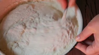 Genç bir kadının elleri, gelecekteki hamur için malzemeleri köydeki ev yapımı klasik mutfakta karıştırıyor.