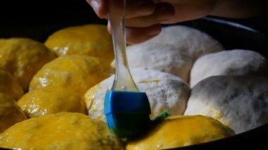 Silikon mutfak fırçası ev yapımı pişirme için çırpılmış yumurtayla hamur toplarını yağlar. Siyah renkte hamur işi.