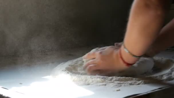 Las manos femeninas amasan la masa en la cocina vintage de la casa en el pueblo. Un rayo de sol cae sobre la masa y la harina volando en el aire. Hornear en casa — Vídeo de stock