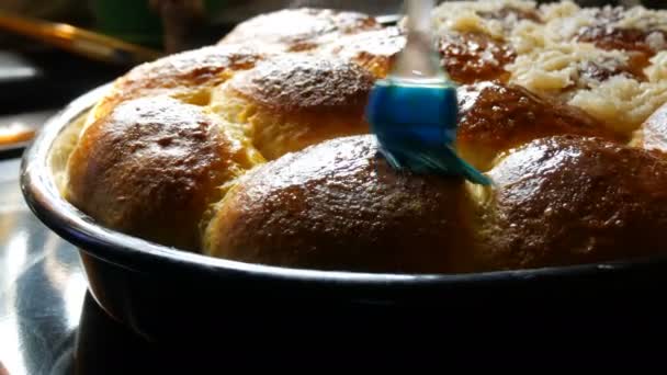 Un cepillo de cocina de silicona especial engrasa el huevo con una deliciosa masa recién horneada en una bandeja para hornear solo del horno. Donuts nacionales ucranianos para hornear con ajo y vapor caliente — Vídeo de stock