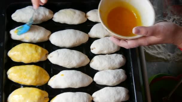 Silikonový kuchyňský kartáč mazá podlouhlé těstovinové kuličky se šlehaným vejcem pro domácí pečení. Těsto na pečivu černé barvy — Stock video