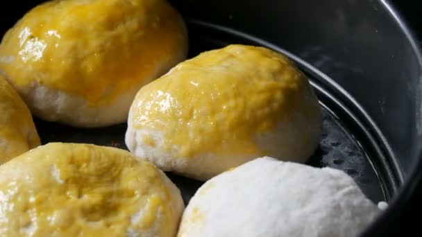 Vista da vicino della cottura fatta in casa su una teglia da forno, il fornaio femminile unge le palline dall'impasto con un uovo in modo che sporgano rosate. Speciale spazzola in silicone da cucina per ingrassare l'impasto . — Video Stock