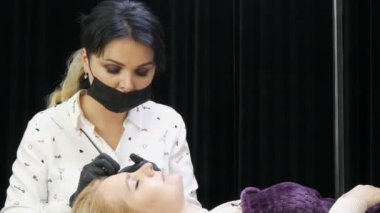 Klinikteki kozmetoloji dolabında. Güzellik uzmanı, koltukta yatan müşterinin kaş şeklini düzeltir. Mikropatinaj, dövme, kalıcı makyaj..