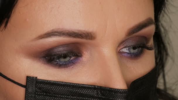 Close-up zicht op het gezicht van jonge mooie stylist vrouw schoonheidsspecialiste in zwart medisch masker. — Stockvideo