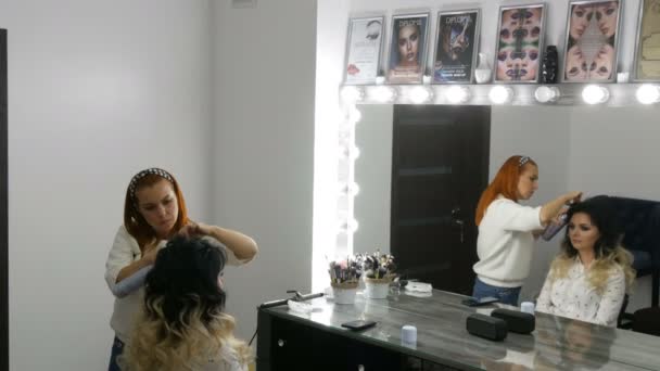 Le 20 septembre 2019 - Kamenskoye, Ukraine : Une coiffeuse fait une boucle de boucles de cheveux avec du fer à friser spécial. De longs beaux cheveux de couleur noire et blanche d'une jeune femme teints à l'aide — Video