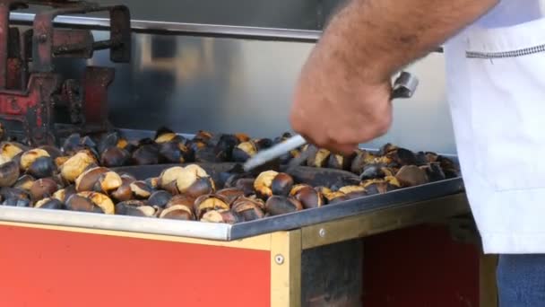 男推销员正在城市街道上烤栗子。 街上的食物，热的栗子 — 图库视频影像