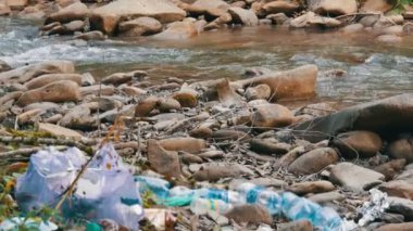 Dağ gibi temiz dere, kayalık sahilde, içinde çöp, plastik şişeler, torbalar var. Çevre kirliliğindeki insan faktörü. Özel çöp giderici