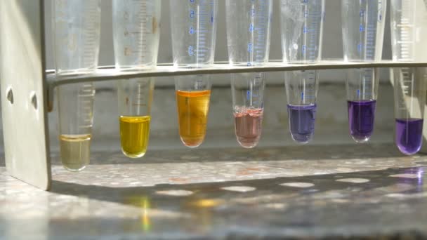 Muchos tubos de ensayo diferentes con agua líquida de color en el laboratorio con reactivos en la ventana vieja con un alféizar de ventana de mármol . — Vídeos de Stock