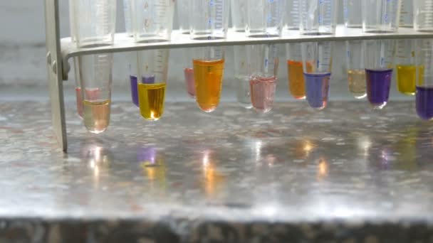 Muchos tubos de ensayo diferentes con agua líquida de color en el laboratorio con reactivos en la ventana vieja con un alféizar de ventana de mármol . — Vídeo de stock