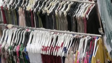 Çeşitli kadın kıyafetleri mağazadaki askılarda asılı duruyor.