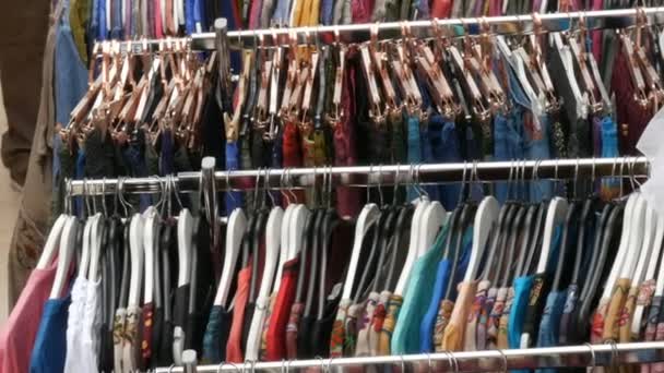 Varios ropa de mujer colgando en fila en perchas en una tienda de ropa — Vídeos de Stock