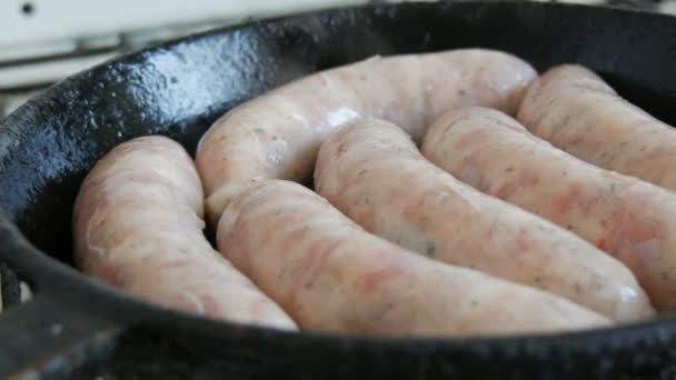 In der heimischen Küche werden dicke fetthaltige, leckere Frischwürste in einer Pfanne gebraten. Gebratene Fleischprodukte, die Würstchen für Bier herstellen. Weißes München oder bayerische Würstchen — Stockvideo