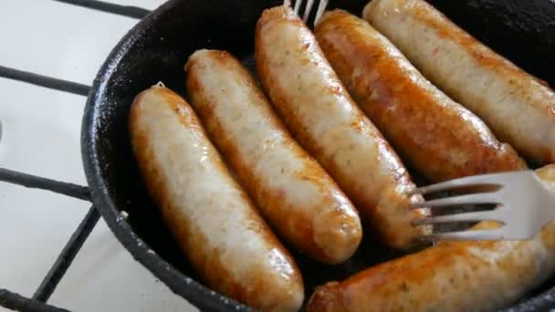 Παχιά λιπαρά νόστιμα φρέσκα λουκάνικα τηγανίζονται σε ένα τηγάνι στην κουζίνα του σπιτιού. Τηγανητά προϊόντα κρέατος που φτιάχνουν λουκάνικα για μπύρα. Πιρούνι μετατρέπει Fried Λουκάνικα — Αρχείο Βίντεο