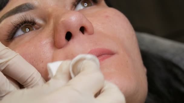 Kosmetolog torka bomullspad läppar under permanent makeup eller läppar microblading tatuering. Göra läpparna konturerade. Vackra händer och patienten ansikte närbild. — Stockvideo